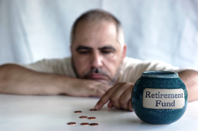 A man sitting at the table with his hand on a jar of coins.