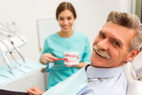 A man and woman in dental uniforms smile for the camera.