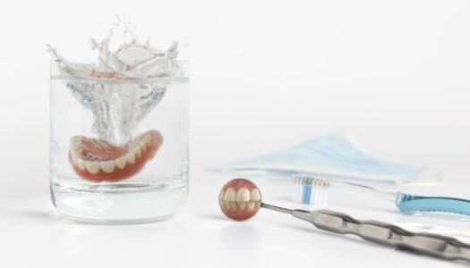 A glass of water with teeth and scissors in it.