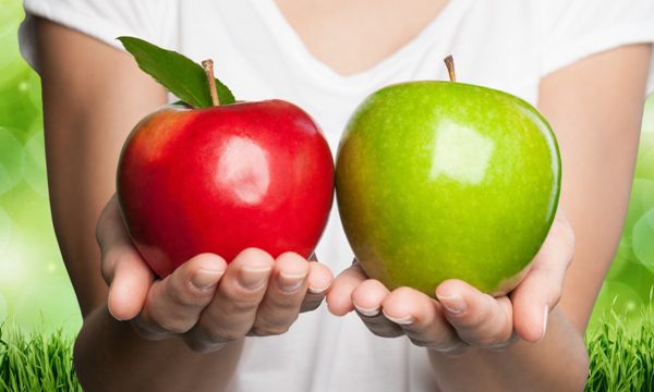 Two hands holding apples in their hands.