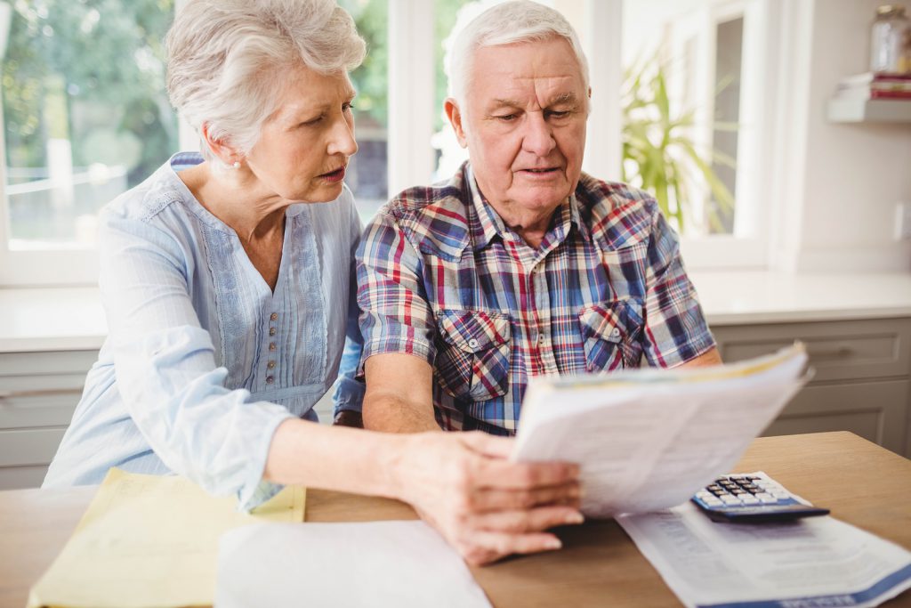 A man and woman looking at papers on a table.