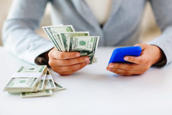 A person holding a cell phone and money.