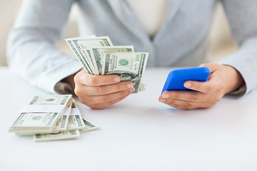 A person holding a cell phone and money.