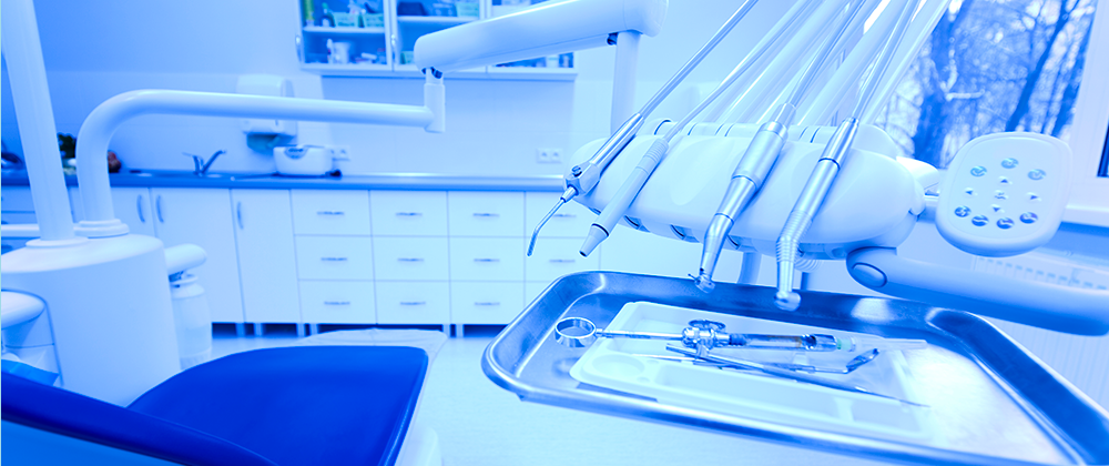 A dentist 's chair in the foreground with other dental equipment.