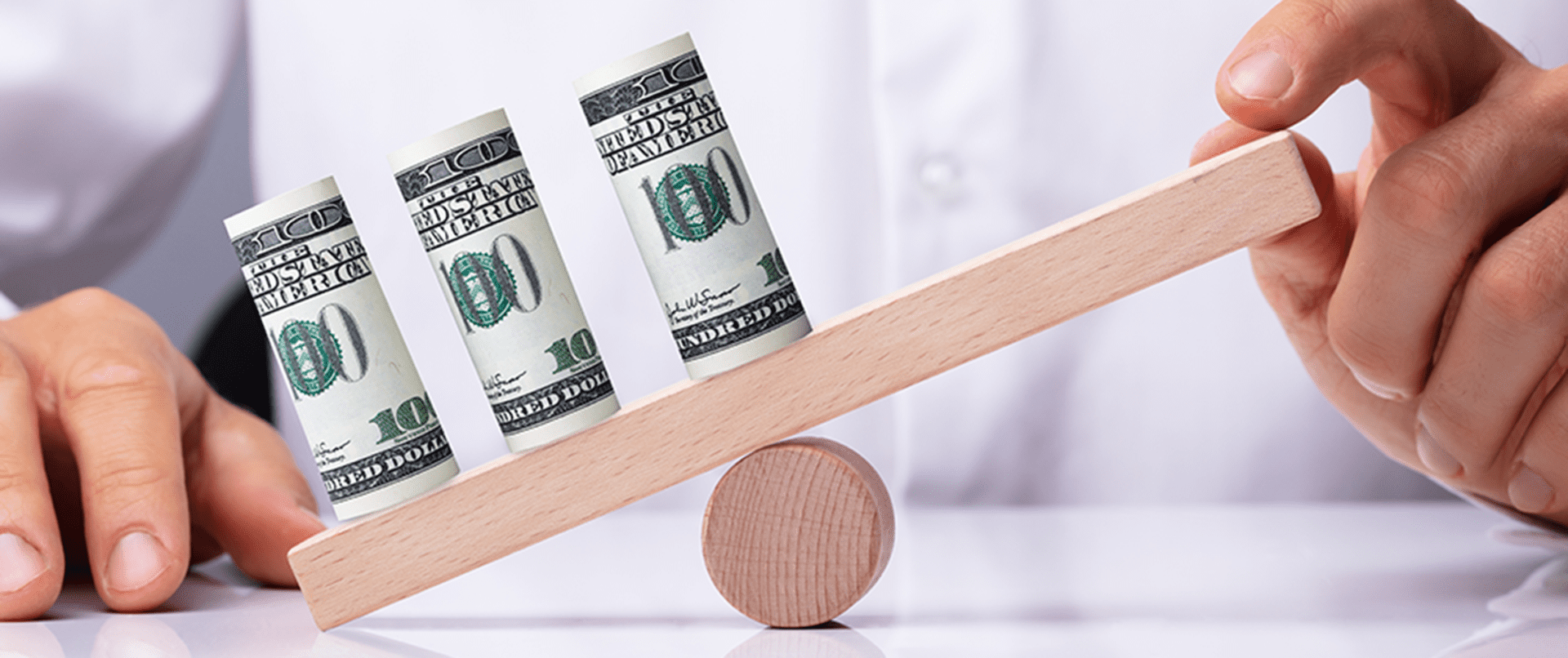 A pair of money rolls on top of a wooden balance beam.